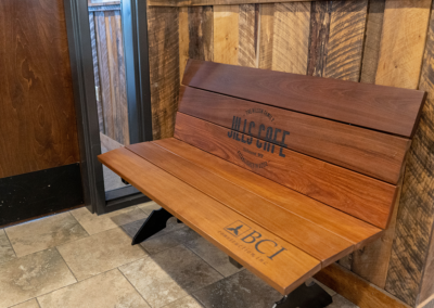 Interior, wood bench at entry way with "Jill's Cafe" and "BCI Construction" engraved on it.